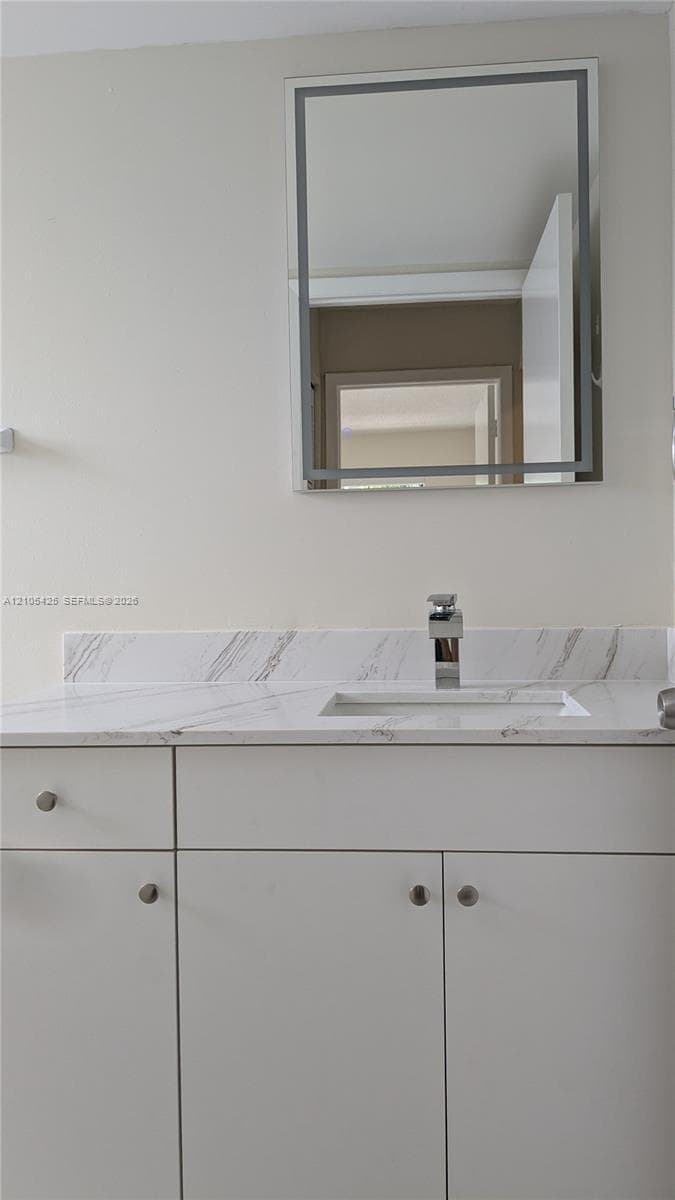 White floating vanity with a polished chrome faucet, rectangular undermount sink, and a framed wall mirror