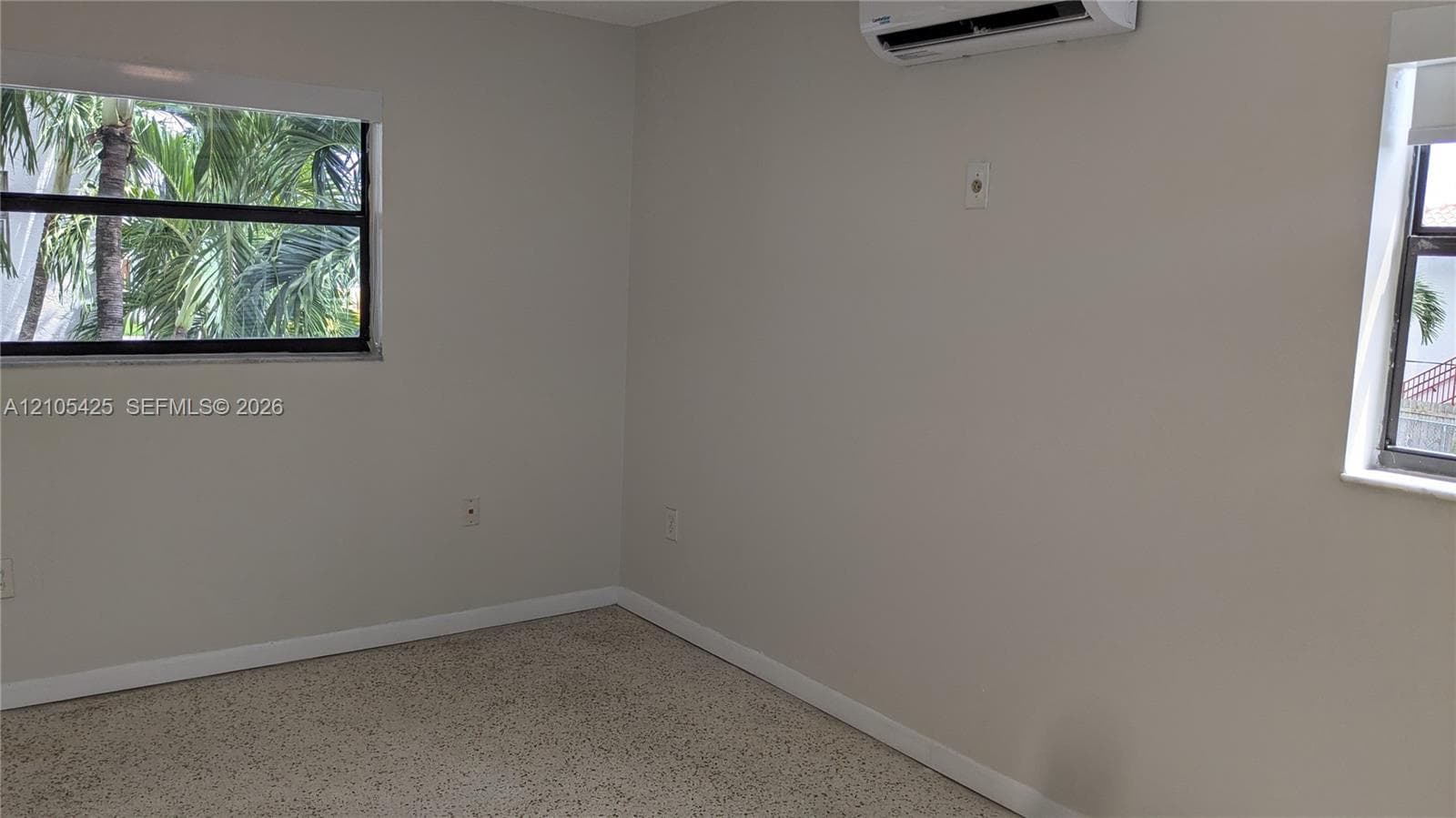 Textured flooring, light-toned walls, and multiple windows with exterior scenery