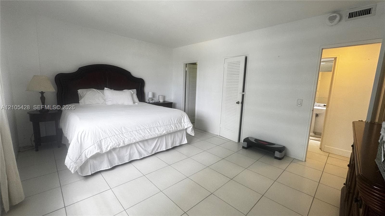 White tile flooring, window with vertical blinds, hinged bifold closet door, and a solid interior door