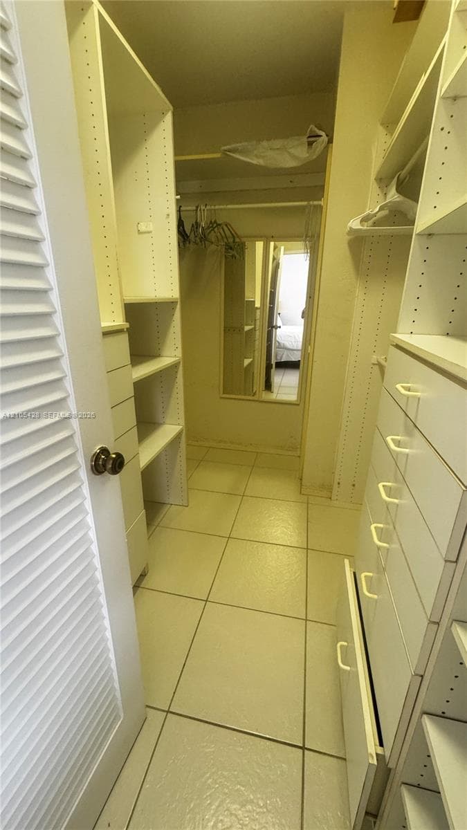 White tile flooring throughout, with a louvered closet door