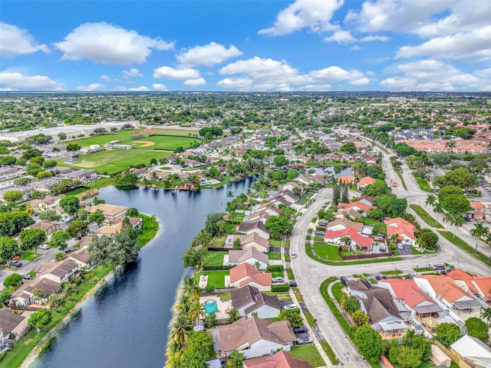 Aerial perspective of waterfront properties featuring meandering canal access and manicured residential grounds