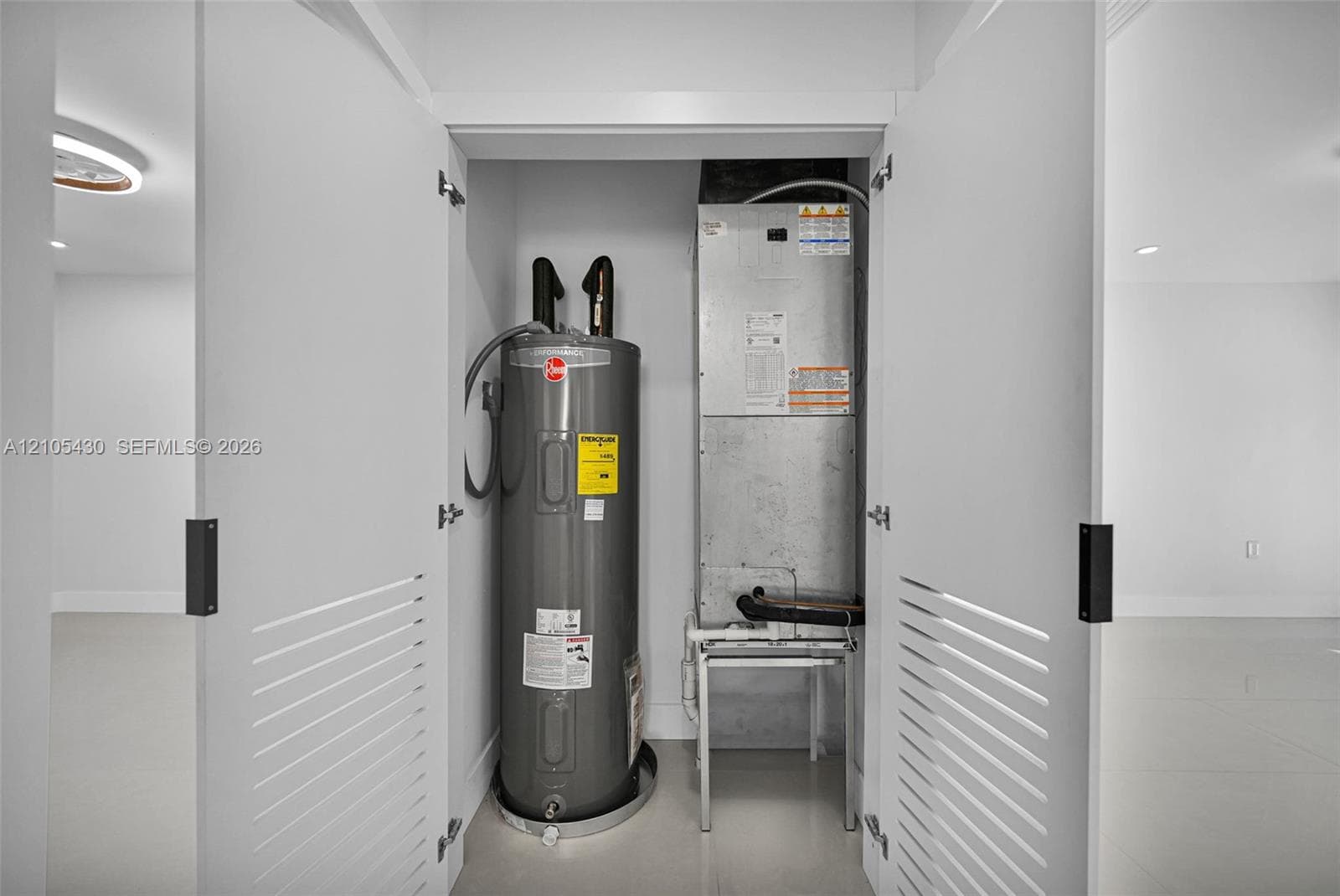 Utility closet featuring double louvered doors, a vertical water heater, and an integrated air handling unit