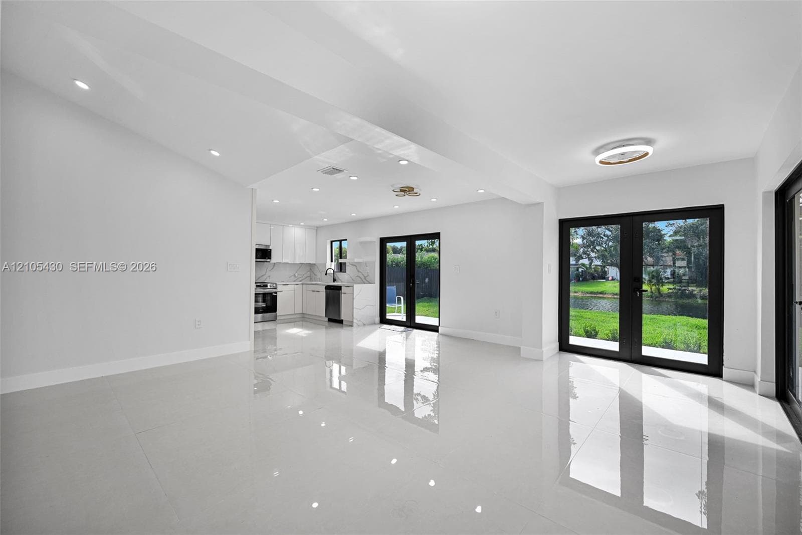 Open-concept interior featuring large-format polished tile flooring, recessed lighting, and kitchen with quartz countertops
