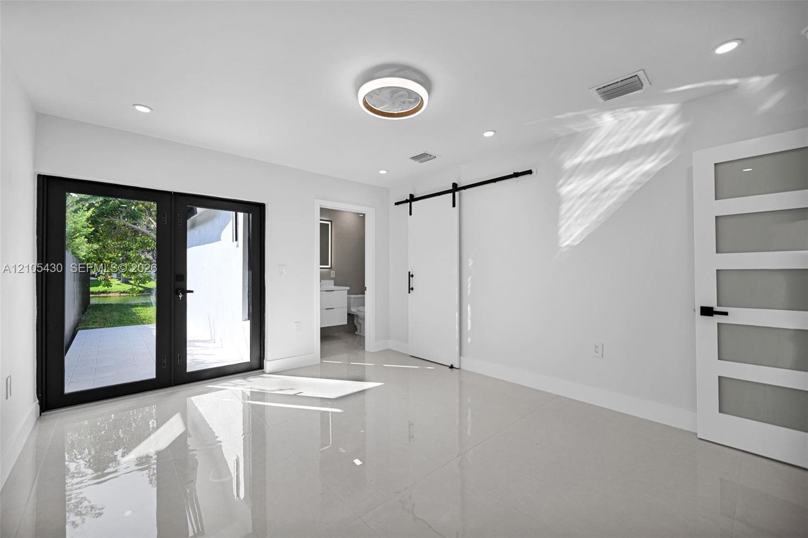 Interior space featuring large-format tile flooring, double glass-paneled exterior doors, a sliding barn-style door, and recessed LED lighting