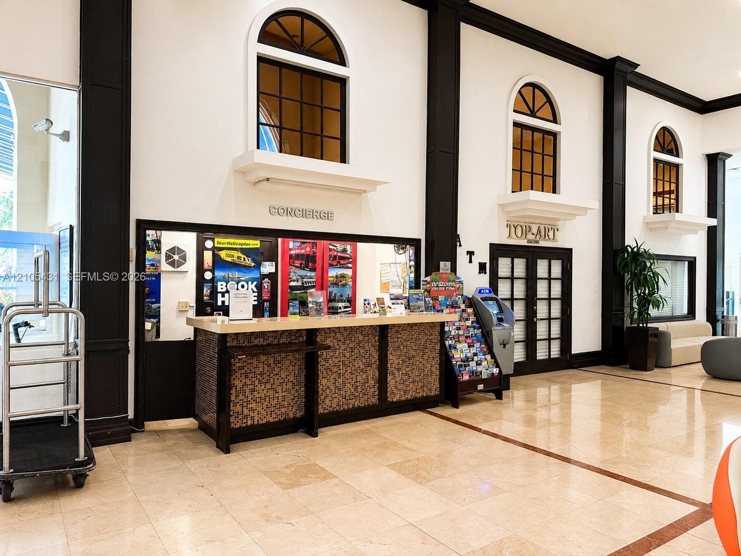 Tiled flooring with contrasting border accents, reception desk with textured paneling, and arched upper-level windows