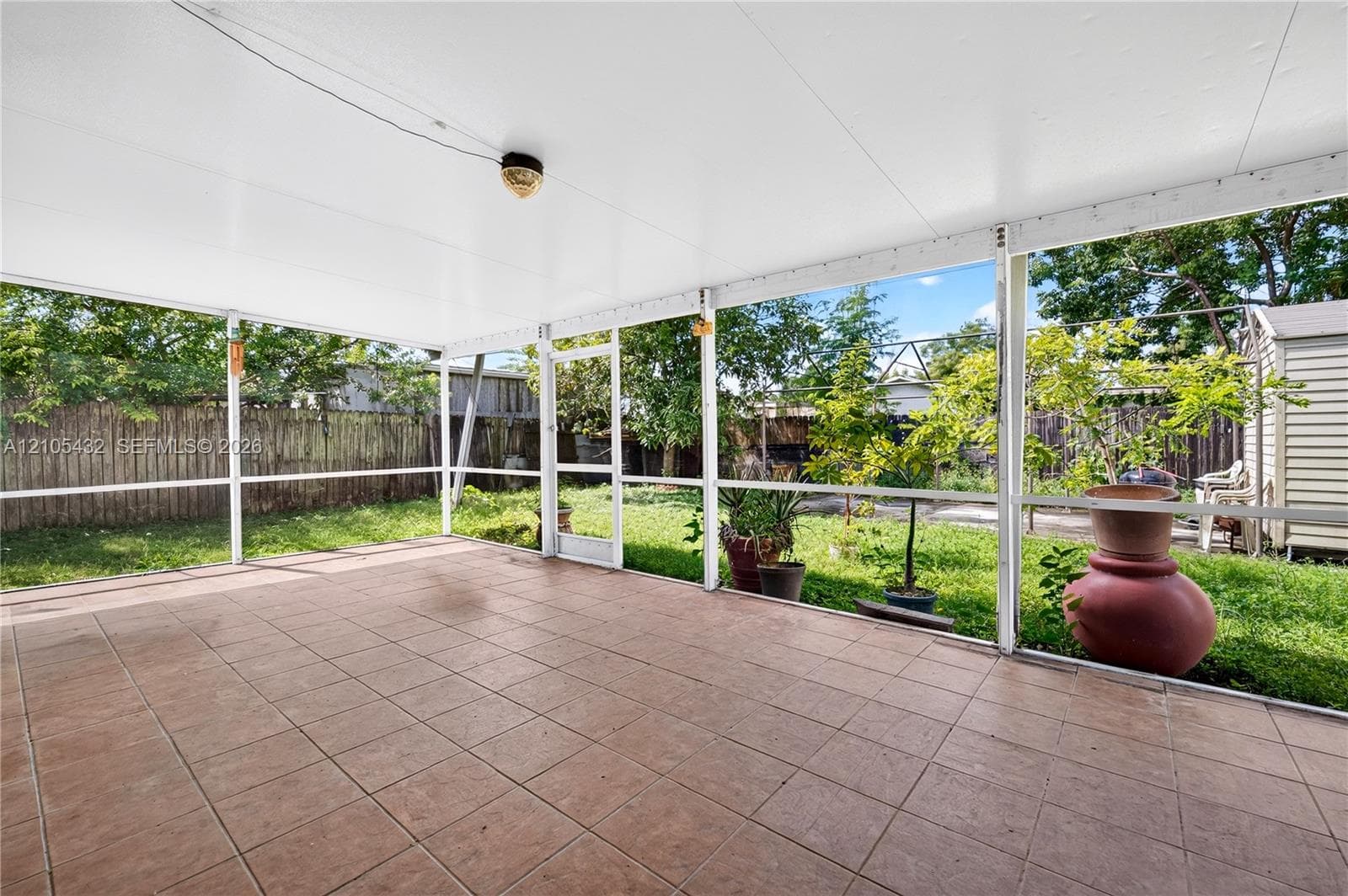 Screened-in covered patio featuring tile flooring, a solid ceiling, and a full-height screen enclosure