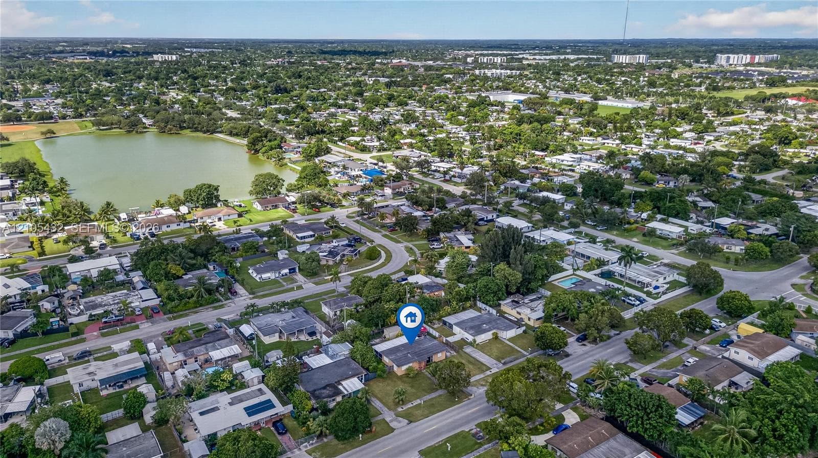 Aerial perspective featuring a single-story residence situated on a landscaped lot with established trees and access to street infrastructure