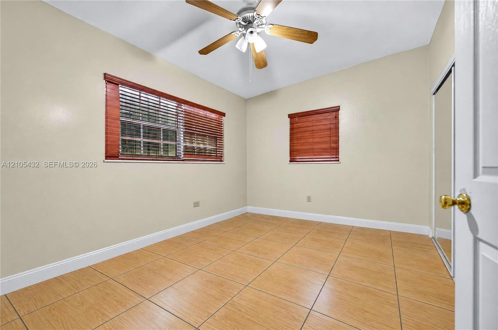 Ceramic tile flooring, ceiling fan with integrated lighting, and mirrored sliding closet doors