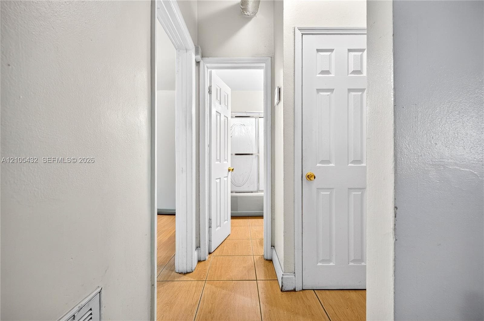 Hallway featuring wood-finish tile flooring, white six-panel interior doors, and door casings