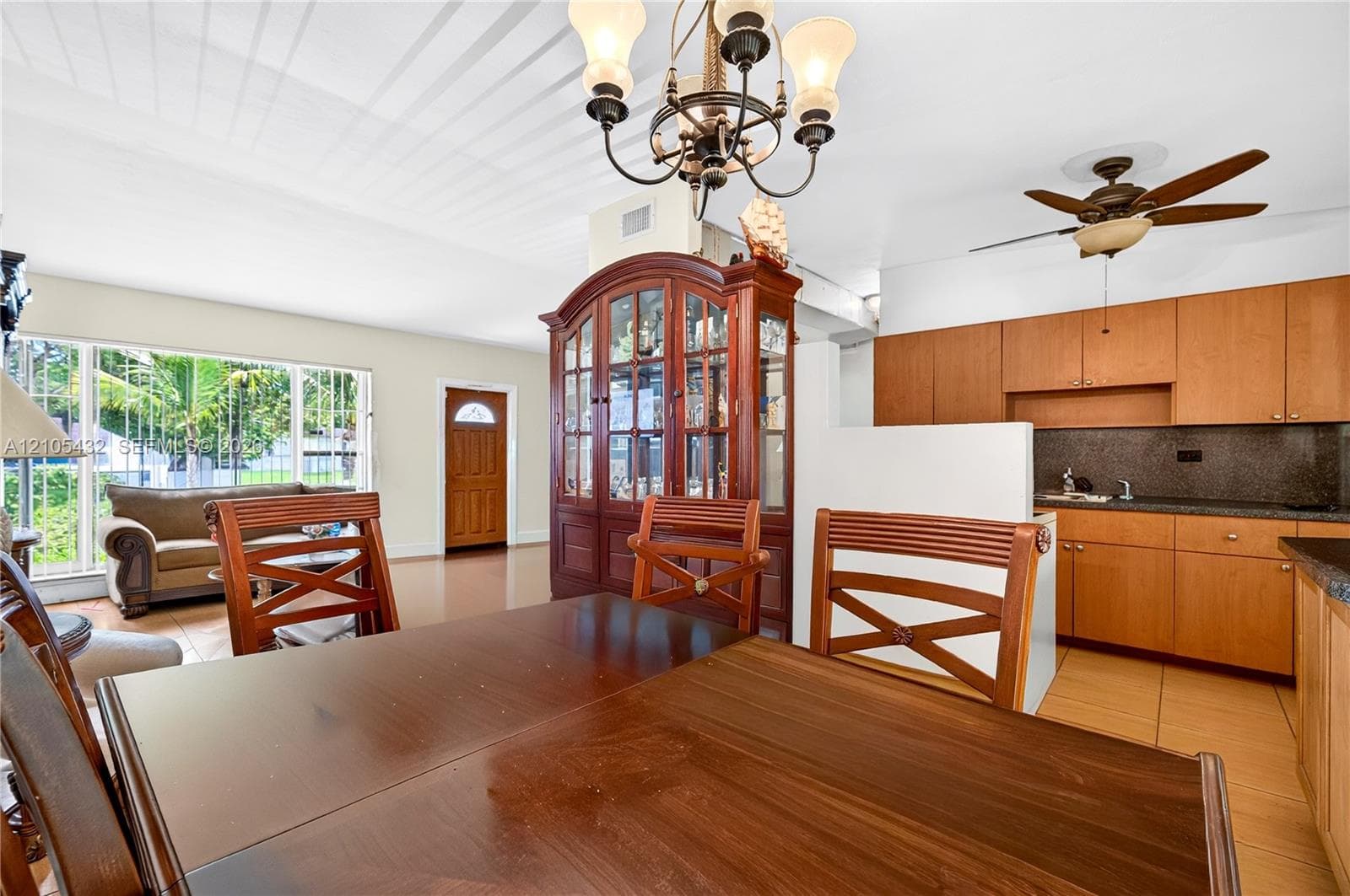 Kitchen featuring wood cabinetry, stone countertops, tile flooring, a multi-arm chandelier, and a ceiling fan