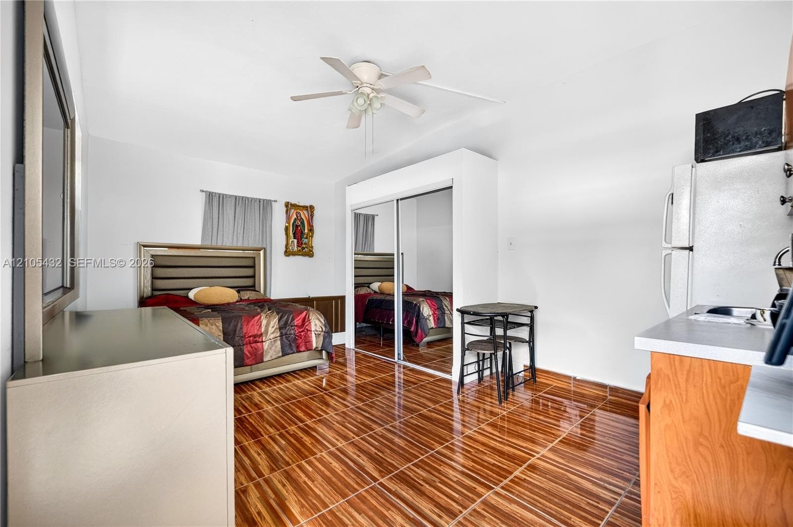 Wood-finish tile flooring, ceiling fan, and built-in closet with mirrored sliding doors