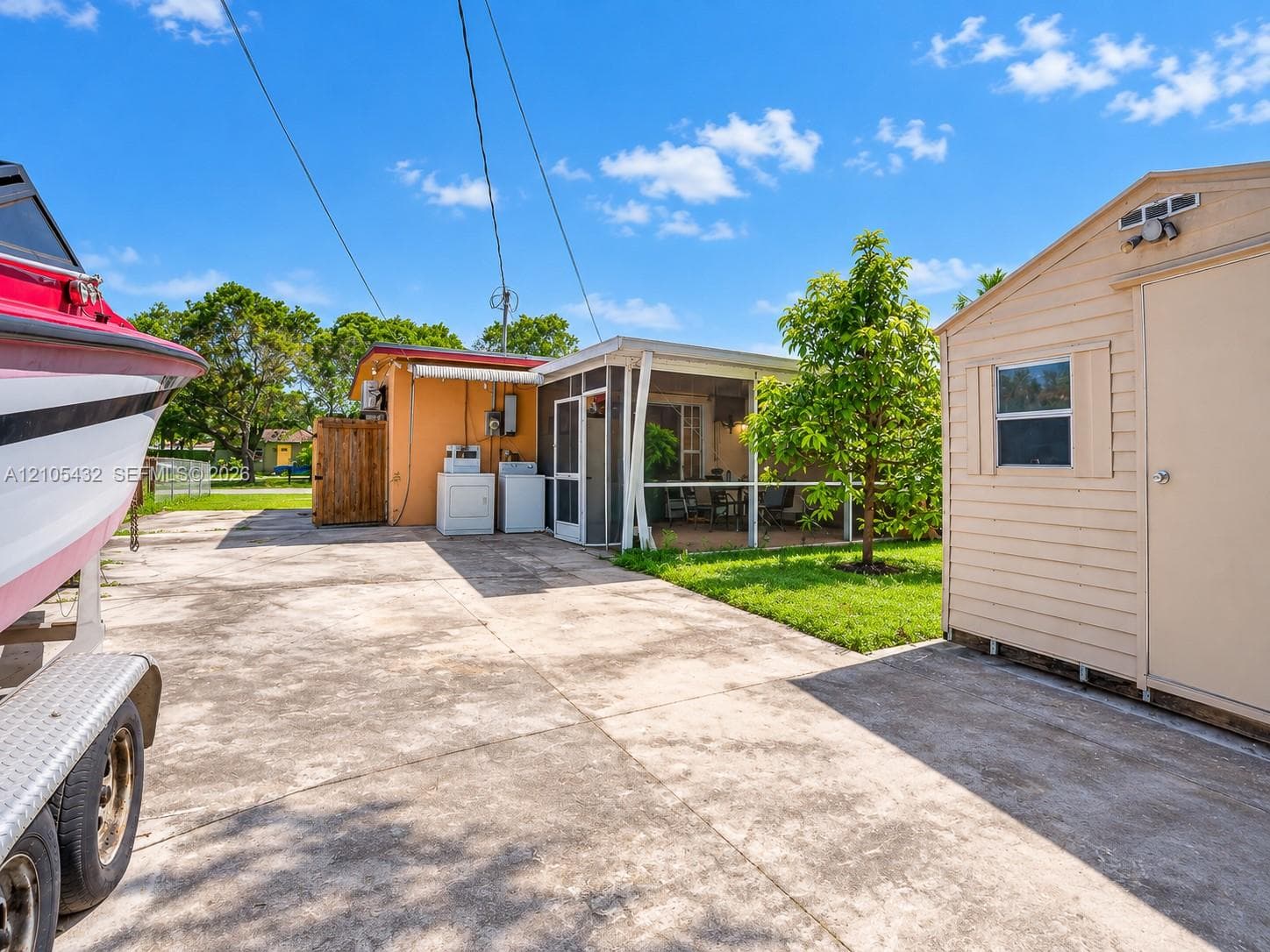 Concrete driveway featuring an exterior laundry station, screened patio, and detached storage shed