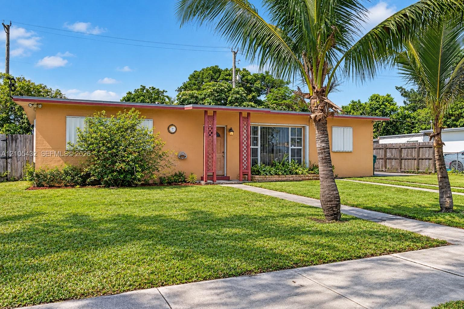Single-story exterior featuring a flat roofline, decorative lattice columns, exterior window shutters, and a concrete walkway