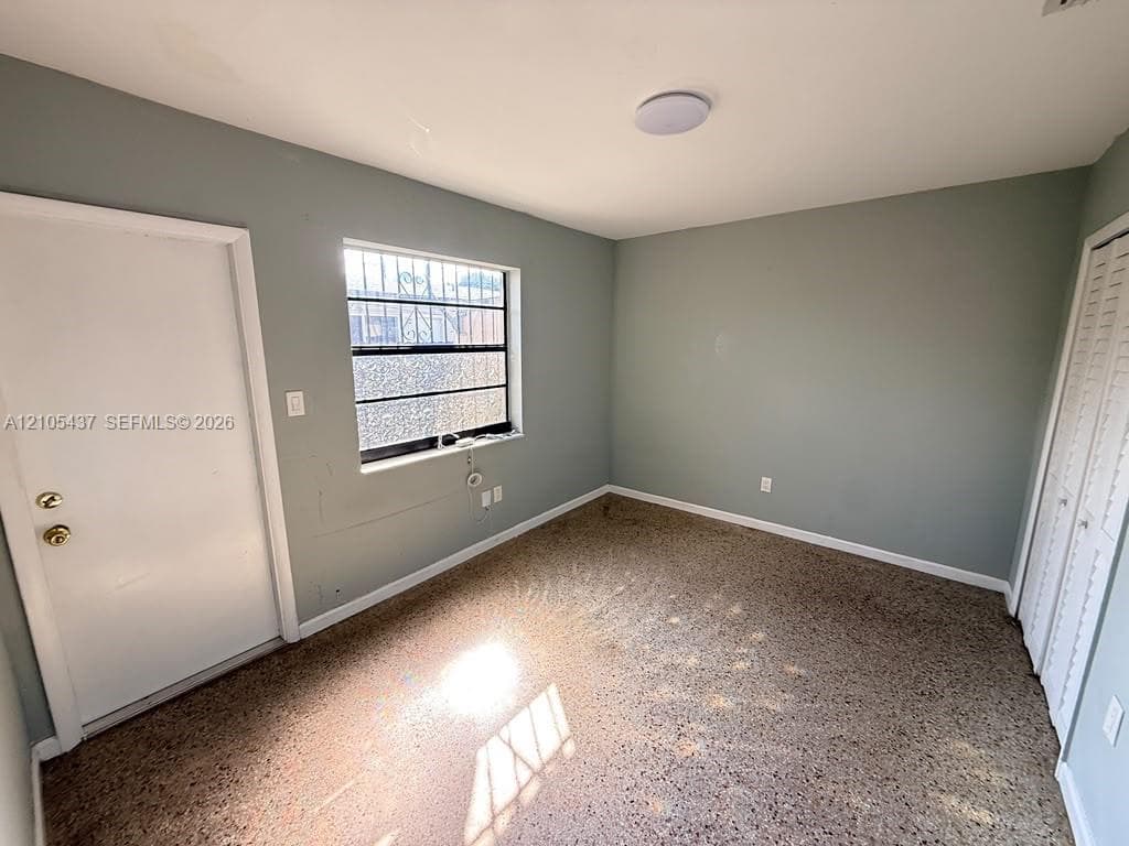 Recessed ceiling light, neutral wall paint, window with security bars, white door, and louvered closet doors
