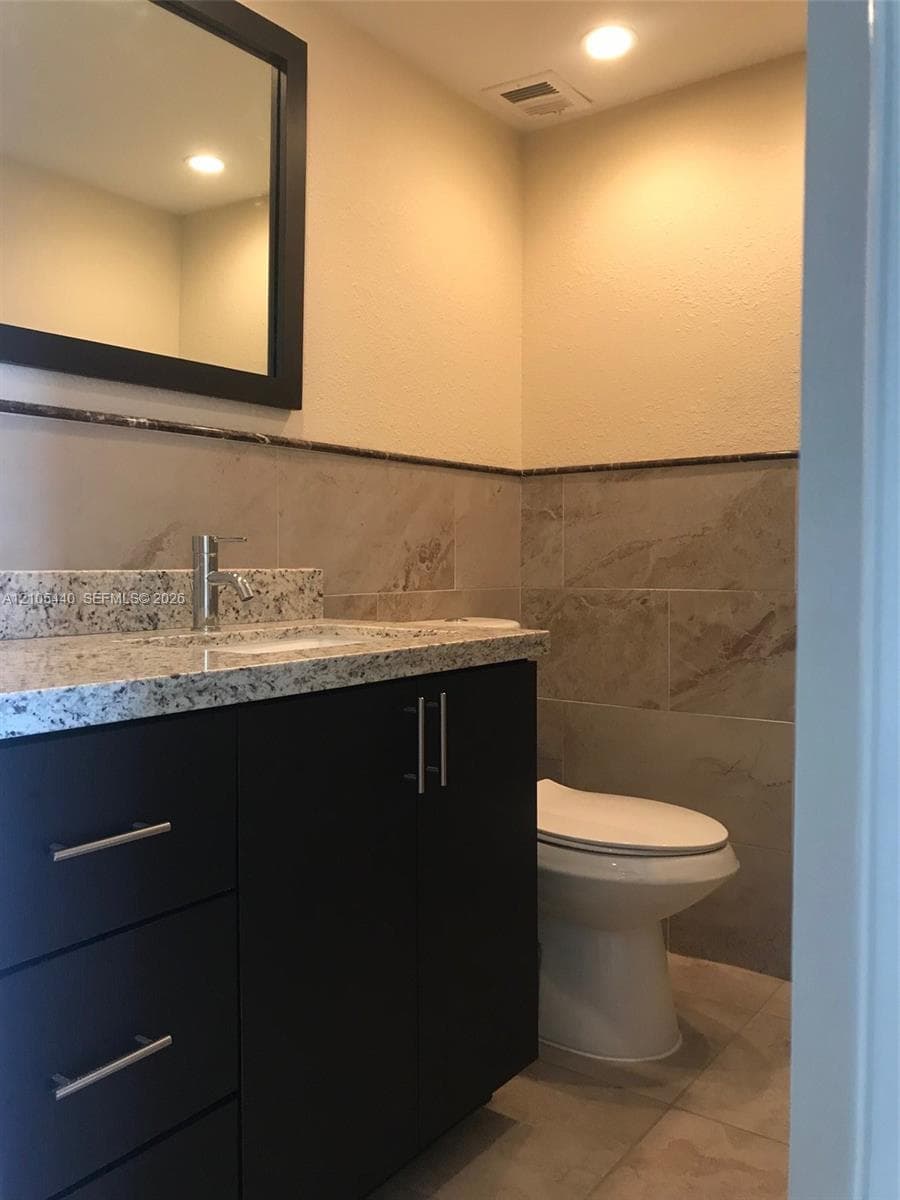 Vanity with a granite countertop, undermount sink, and modern faucet