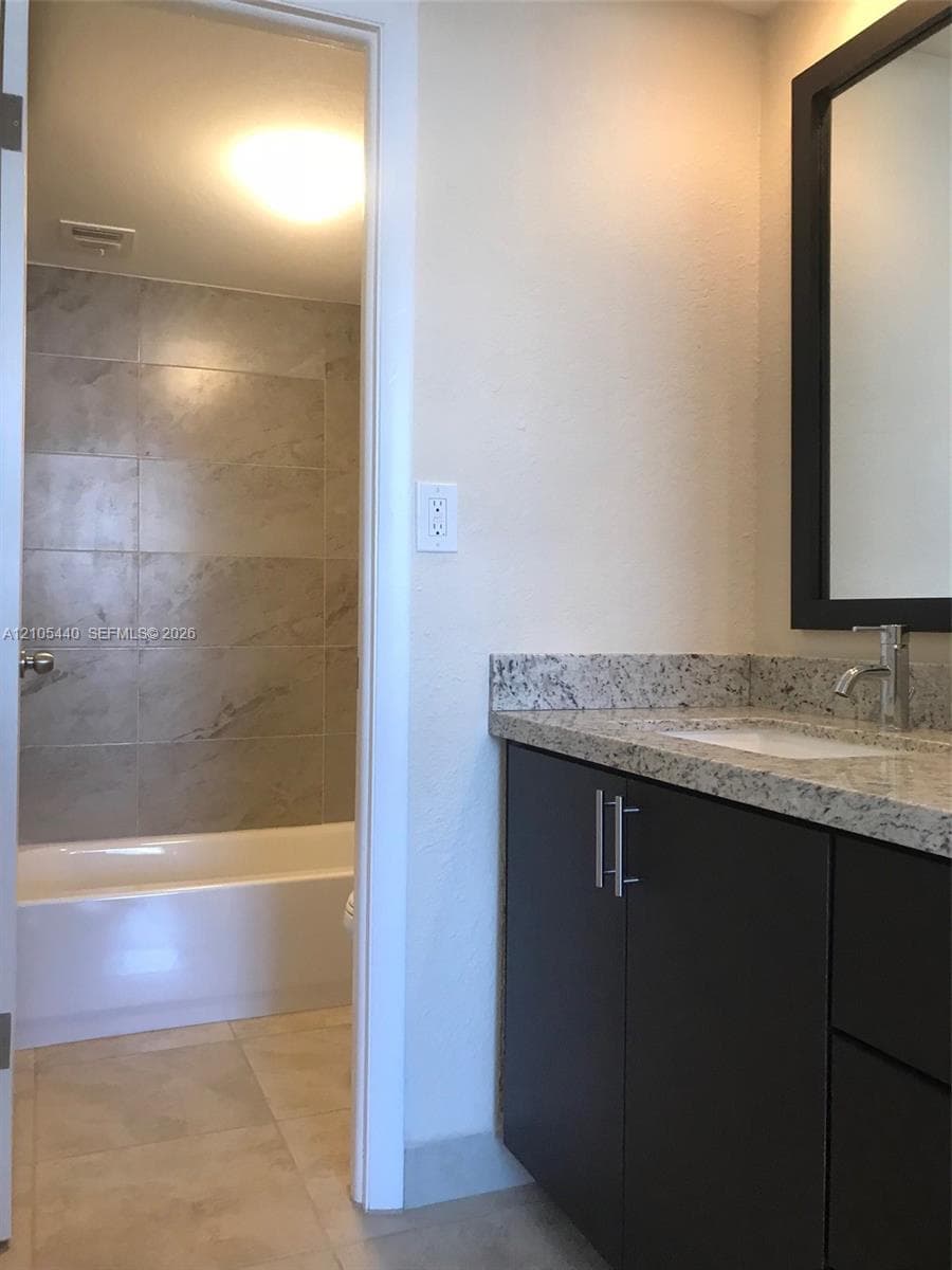 Vanity with granite countertop, integrated sink, and dark cabinetry