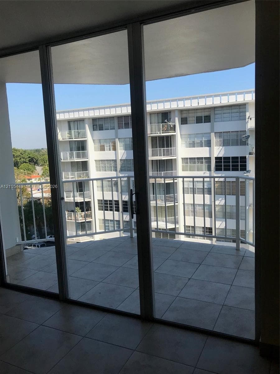 Expansive balcony with tile flooring and white metal railing, accessed through large sliding glass doors