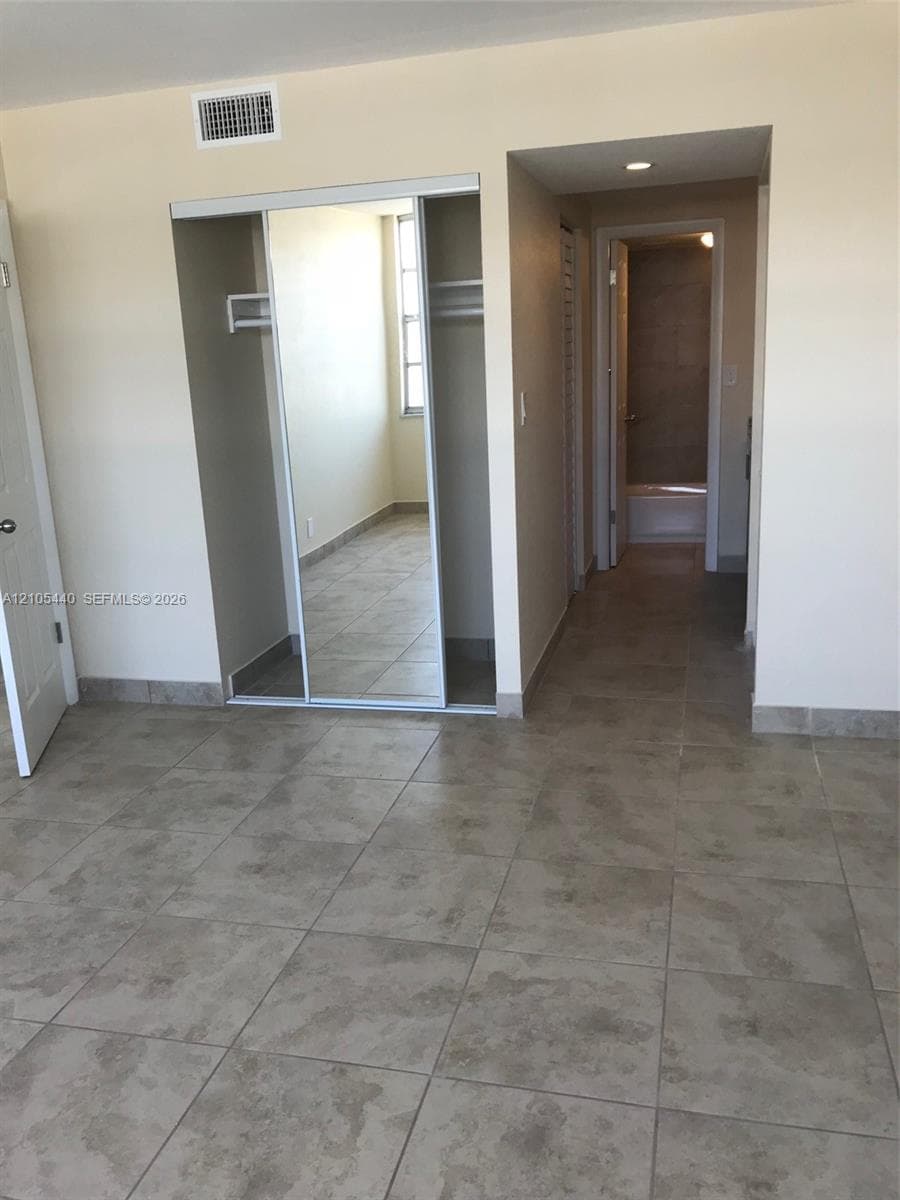 Tile flooring with a neutral finish, mirrored closet doors, and recessed lighting
