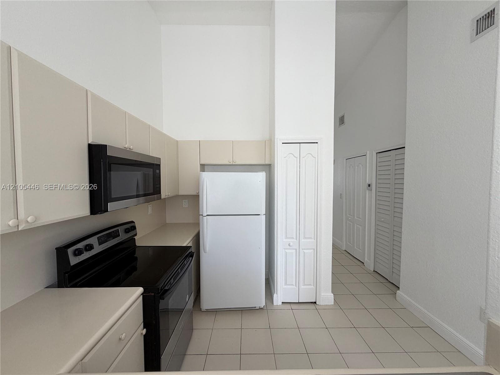 Tiled flooring throughout with a window featuring dark curtains, and a white door