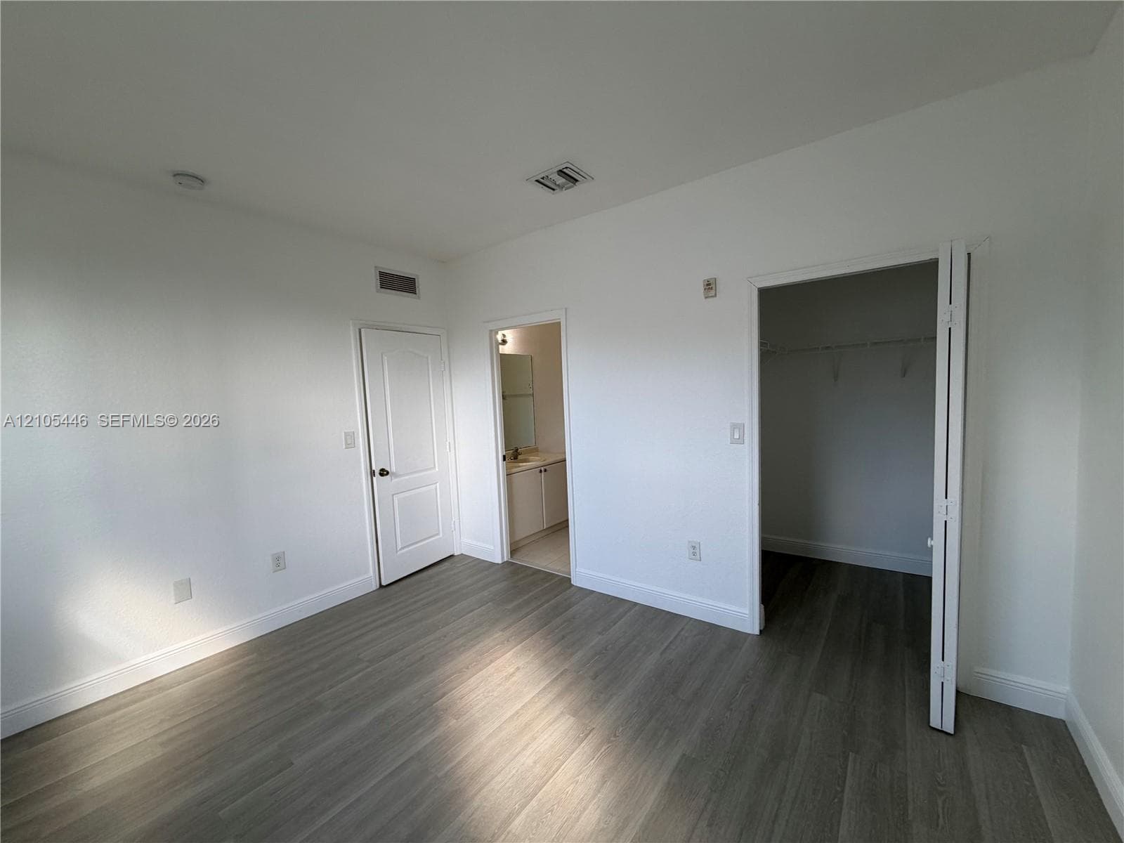 Light wood-finish flooring, white walls, and multiple windows