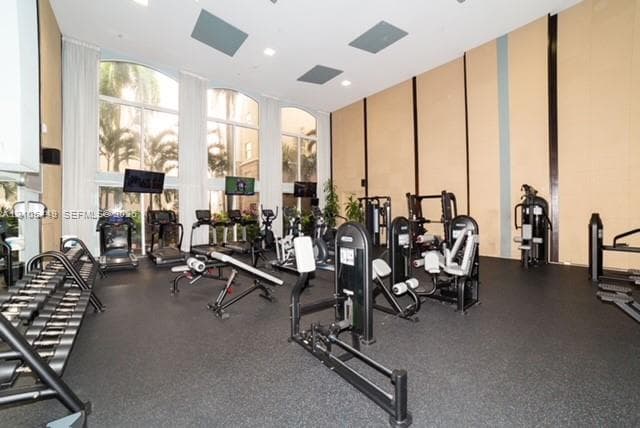 Fitness center featuring an assortment of exercise equipment, floor-to-ceiling arched windows, and recessed lighting