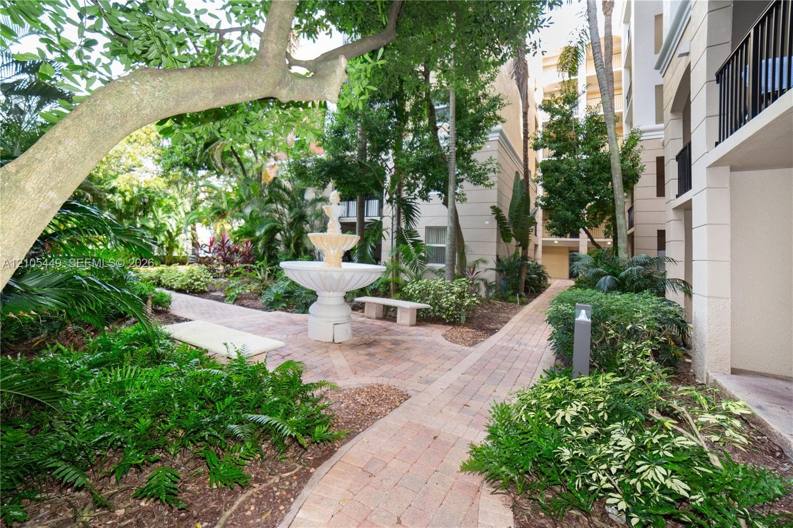 Landscaped courtyard featuring a tiered fountain, paver pathways, and mature trees