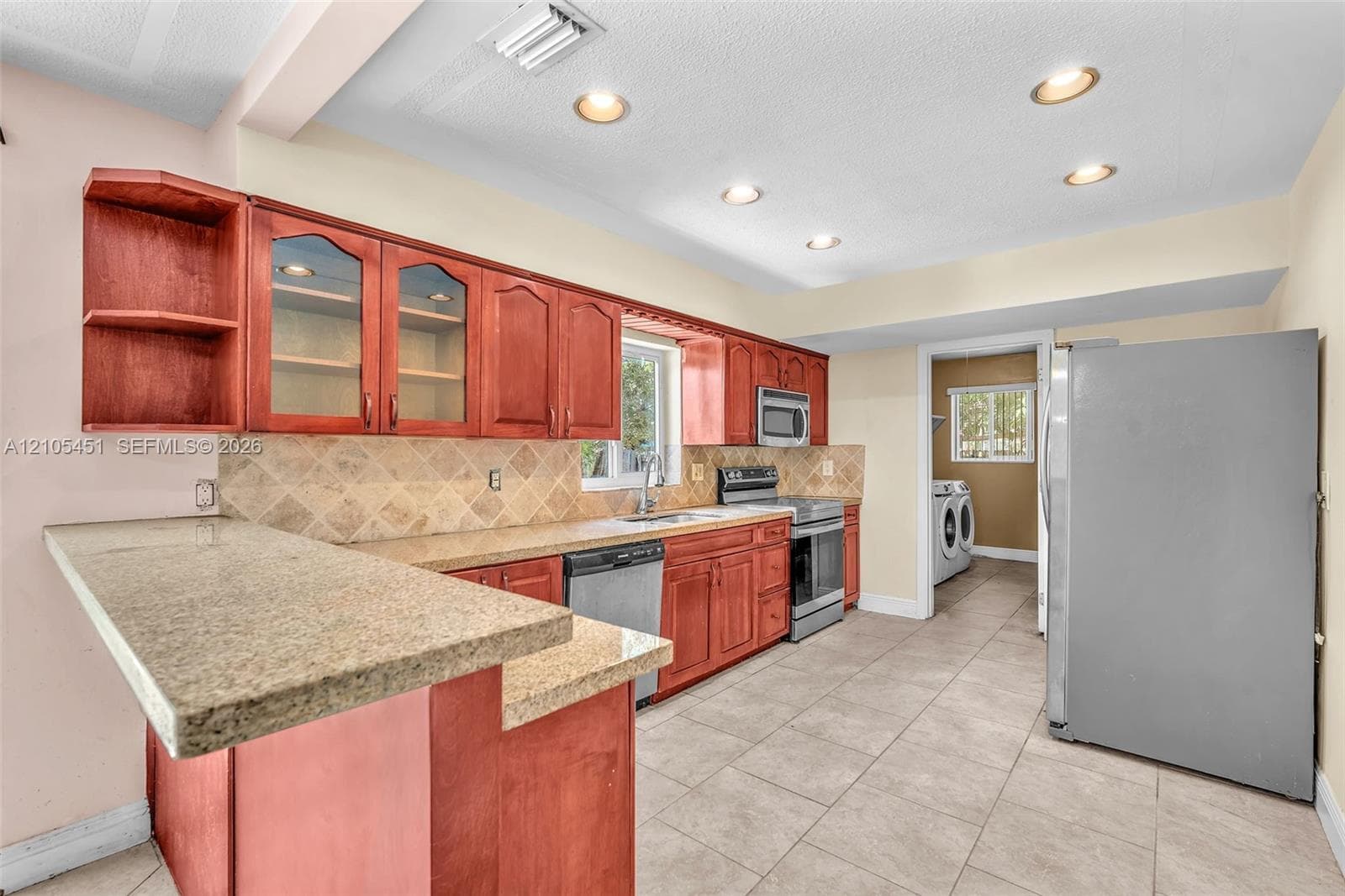 Kitchen featuring wood cabinetry, stone-surface countertops, tile backsplash, tile flooring, and recessed lighting