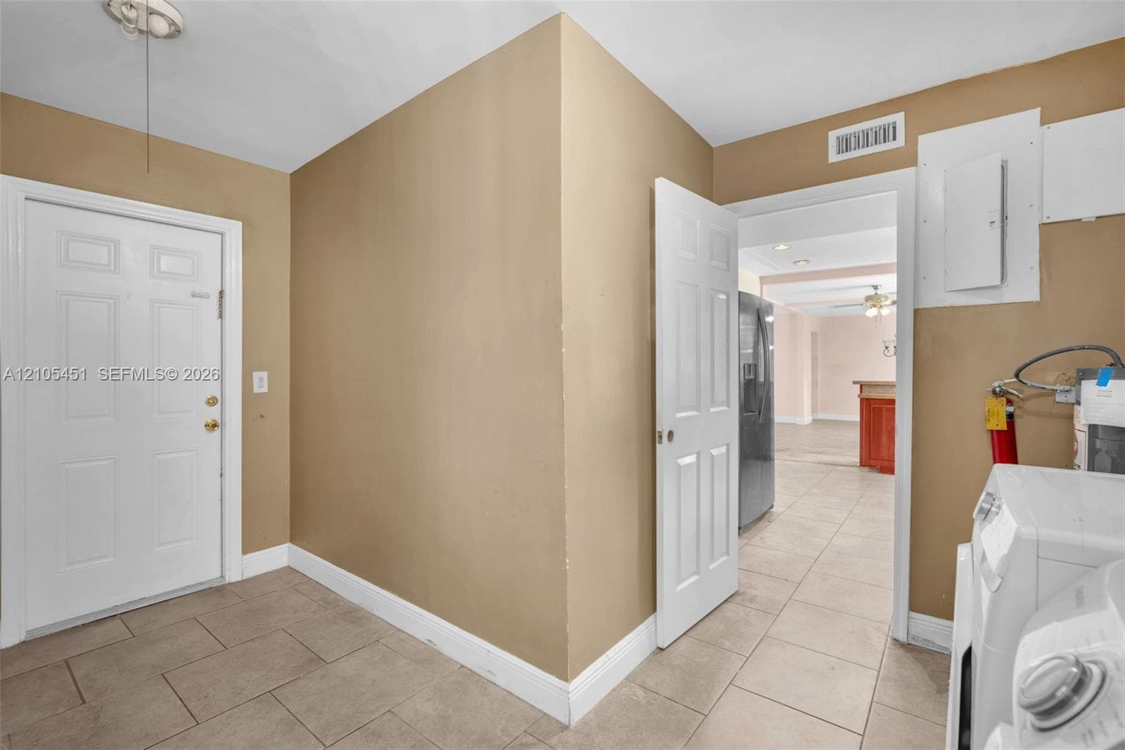 Neutral-toned interior featuring large-format ceramic tile flooring, six-panel white interior doors, and a dedicated utility space