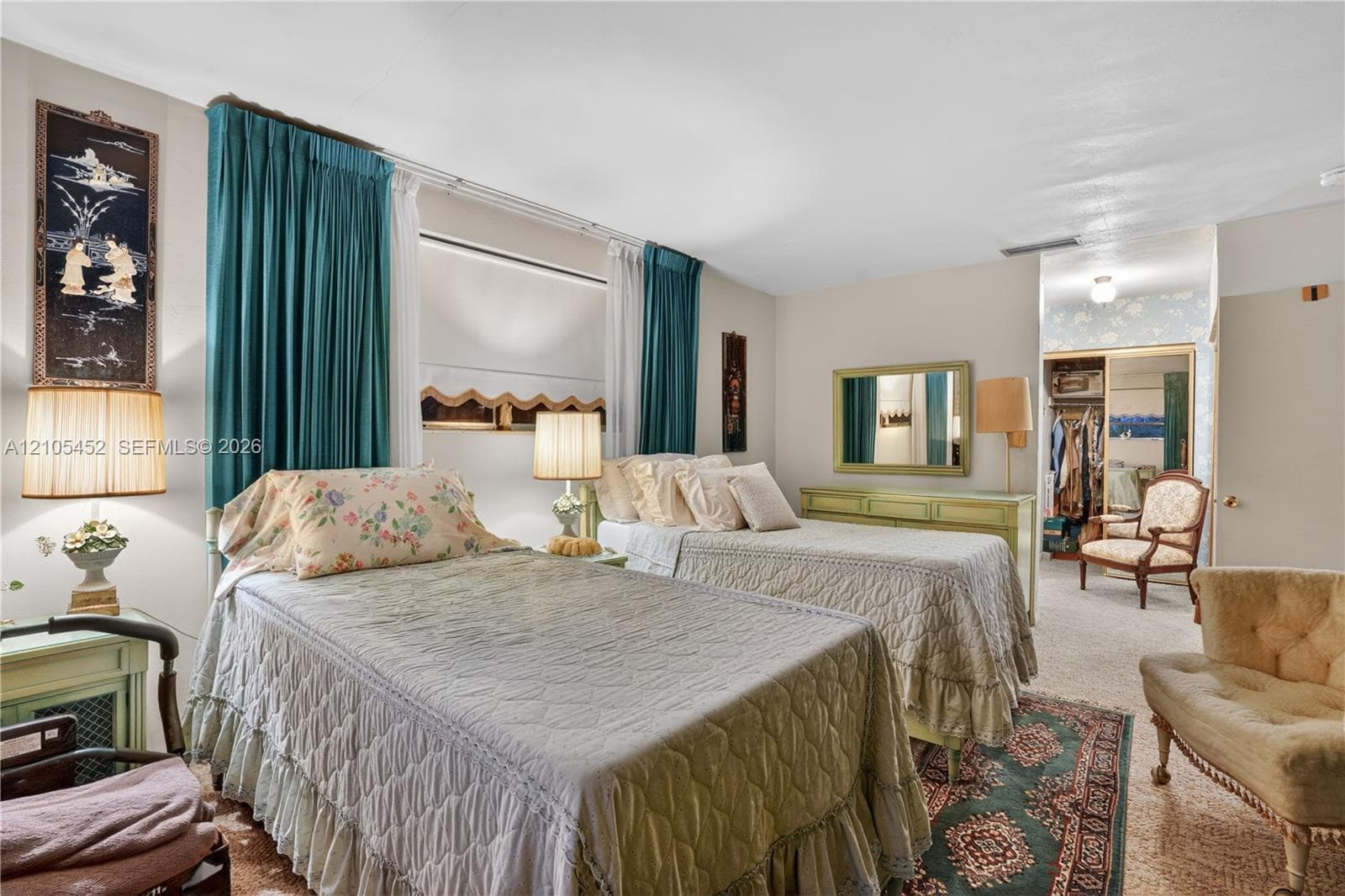 Neutral-toned bedroom featuring carpeting, large window with multi-panel treatment, and a walk-in closet with sliding mirrored doors