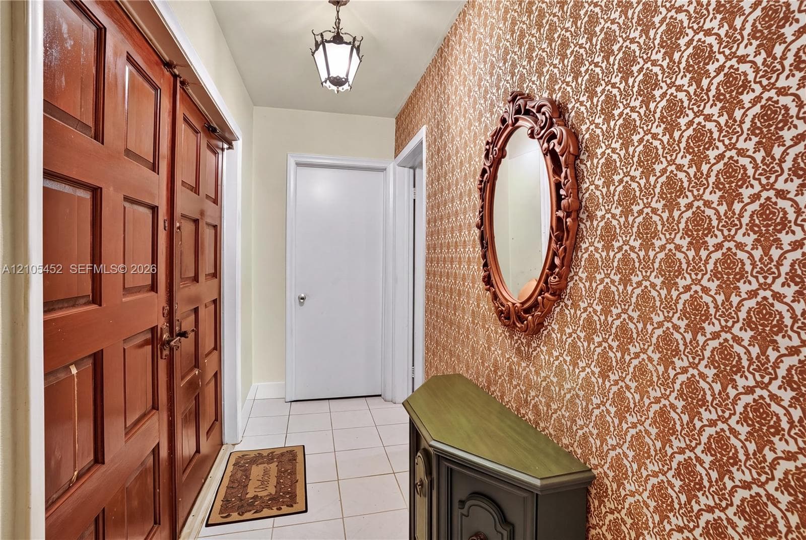 Entryway featuring double wood-paneled doors, ceramic tile flooring, and patterned wallcovering