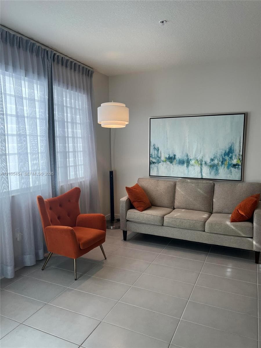 Tile flooring with light grout lines, ceiling-mounted light fixture, and floor-to-ceiling sheer curtains