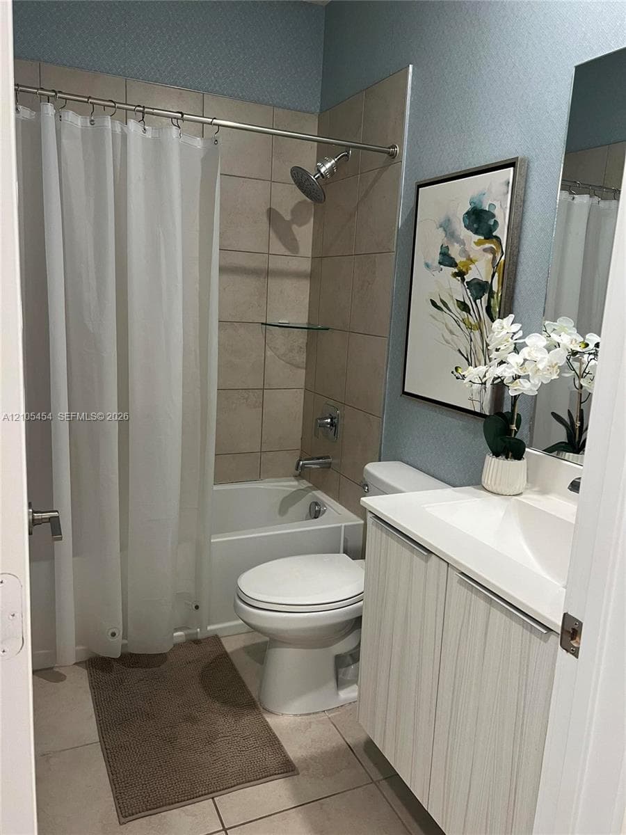 Ceramic tile flooring, tub and shower combination with tiled surround, white vanity with integrated sink, and wall-mounted mirror