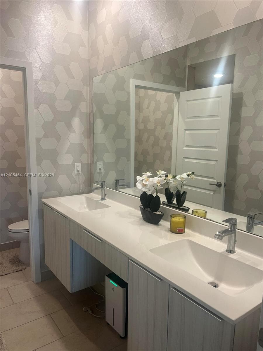 Dual rectangular basin vanity with chrome faucets, a full-width mirror, and geometric pattern wall covering
