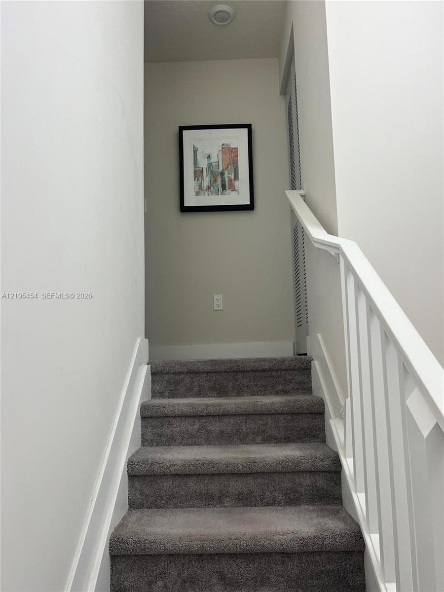 Staircase with gray carpeting and white handrails