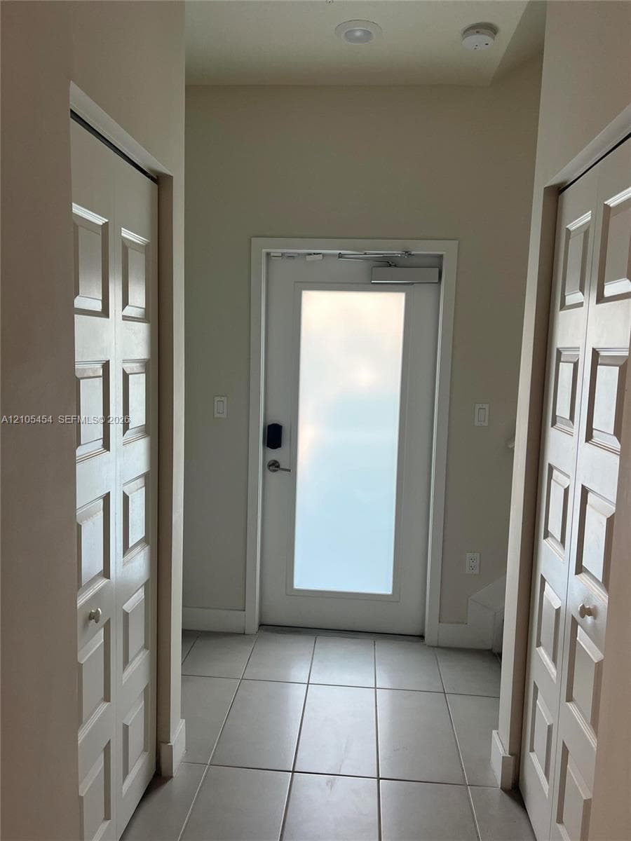 Entryway featuring tile flooring, a frosted glass panel door with a smart lock, and recessed ceiling lighting