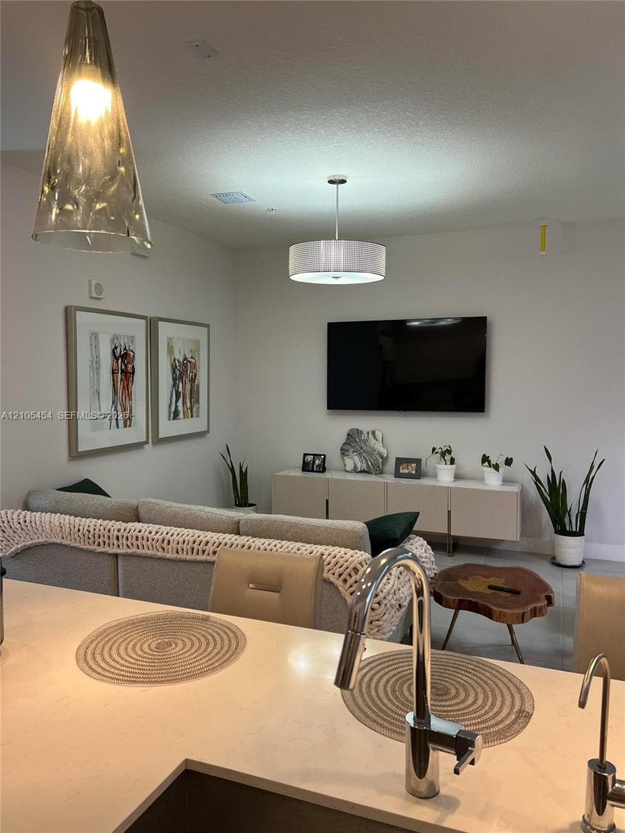 Integrated living space with a kitchen island, contemporary pendant lighting, recessed ceiling lights, wall-mounted television, and a built-in media console