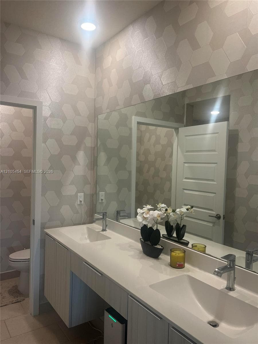 Dual vanity with integrated sinks, modern wall-mounted cabinetry, expansive mirror, and recessed lighting