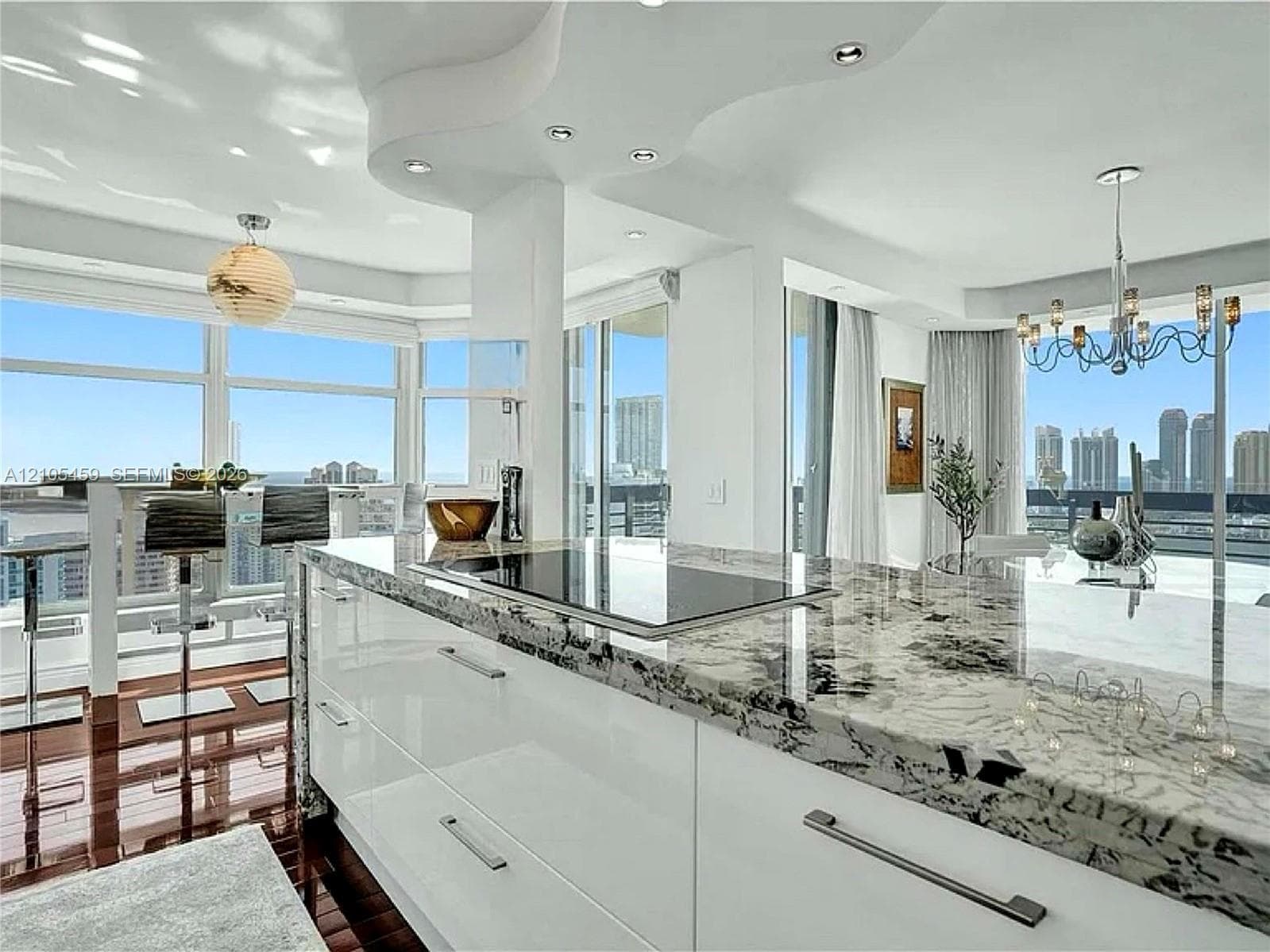 Sleek kitchen island with a built-in cooktop and stone countertop, open concept living area, recessed lighting, expansive floor-to-ceiling windows, and wood-finish flooring