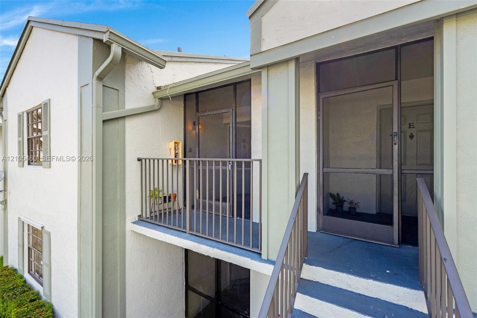 Exterior stucco finish with accent trim, screened-in balcony with metal railing, and screened entry door
