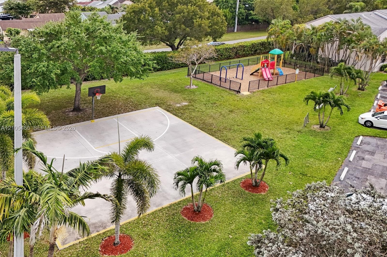 Basketball court with a hoop and a fenced playground area