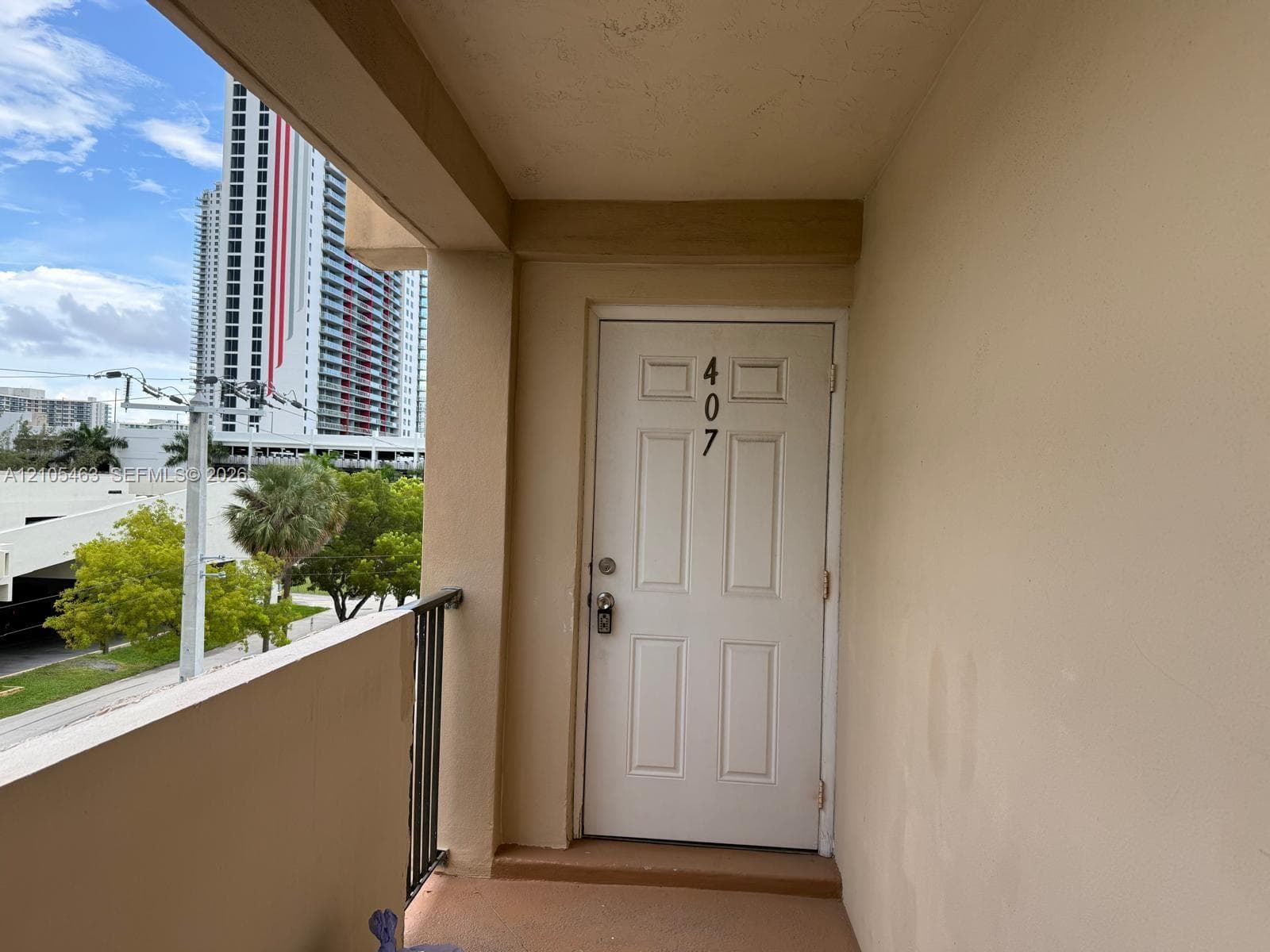 Balcony entrance with a paneled door, black metal railing, and a painted concrete floor