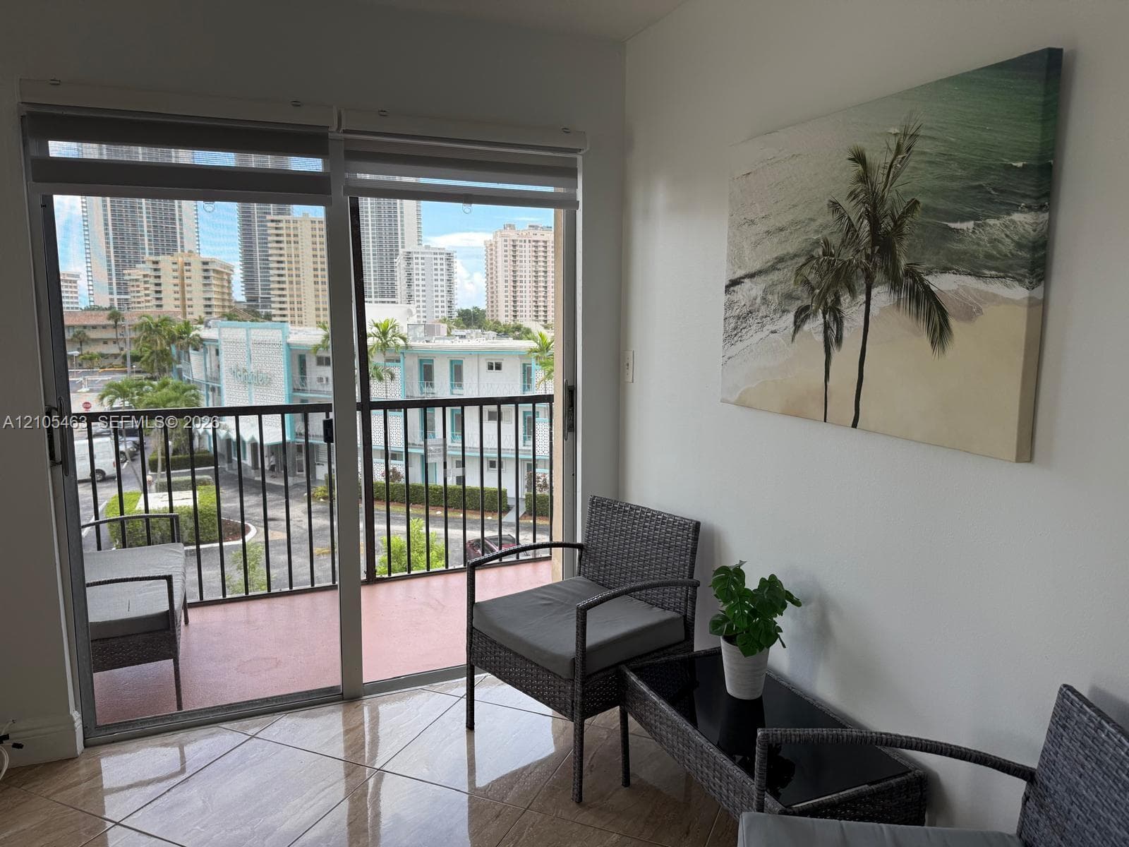 Sliding glass doors opening to a private balcony with a metal railing, overlooking city buildings