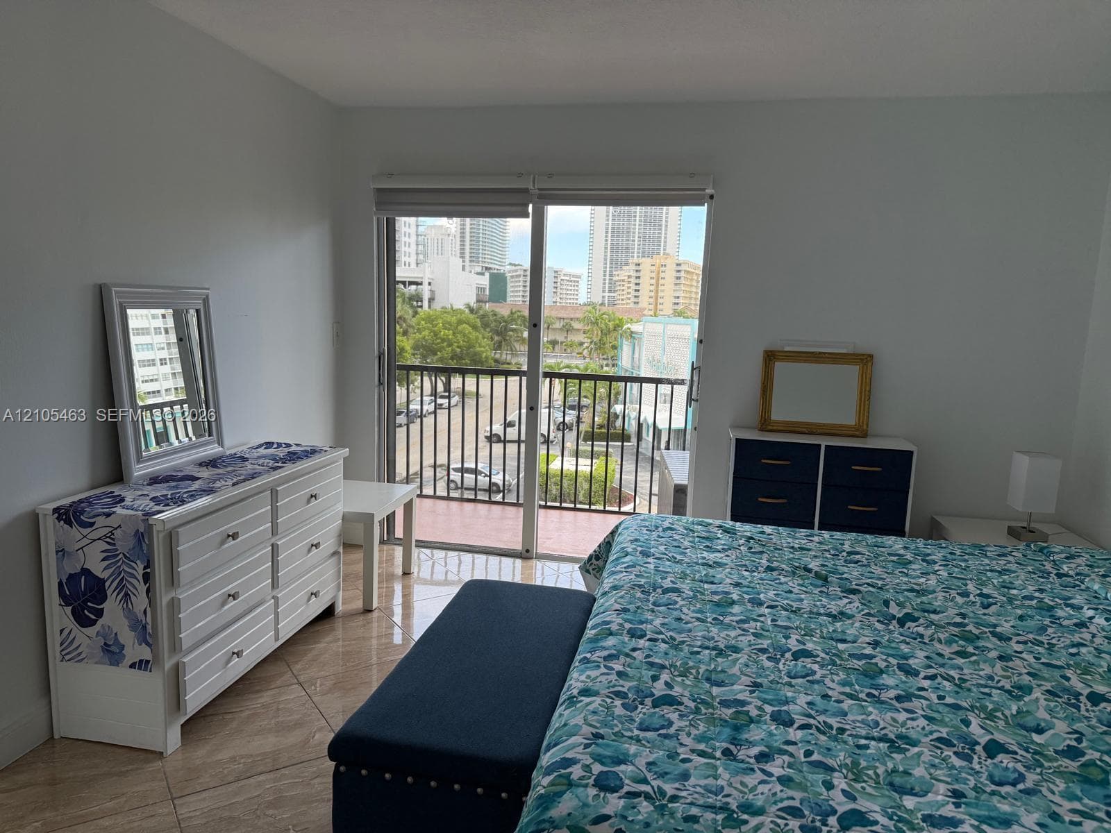 Slider door to balcony with metal railing, tile flooring, and city backdrop