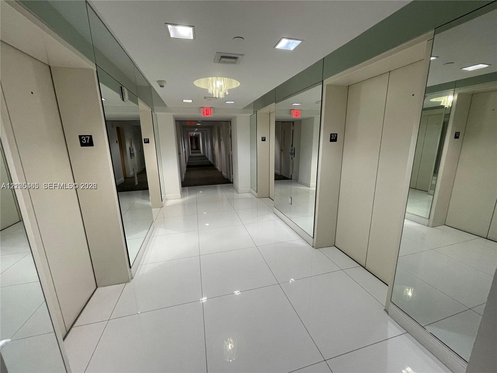 Polished tile flooring, recessed ceiling lighting, decorative ceiling fixture, mirrored wall panels, and light-toned walls