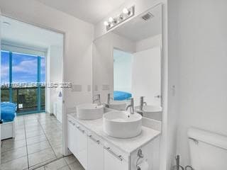 Double vanity with vessel sinks, white cabinetry, and a large wall-mounted mirror