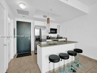 Kitchen featuring a peninsula island, stainless steel refrigerator, built-in microwave, and tile flooring