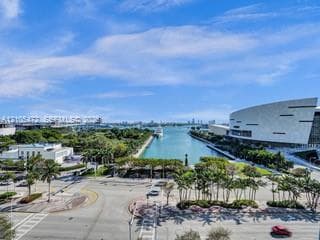 Cityscape with prominent waterfront, lush landscaping, modern architectural structures, and urban infrastructure