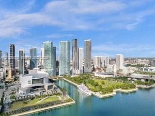 Downtown cityscape featuring numerous high-rise buildings, waterfront access, a large public park, and a prominent performance venue