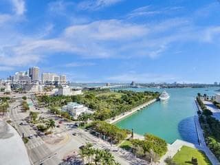Expansive water feature, urban skyline, verdant landscape, visible roadways, distant bridge