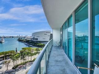 Expansive outdoor balcony with glass railing, providing water and city skyline elements